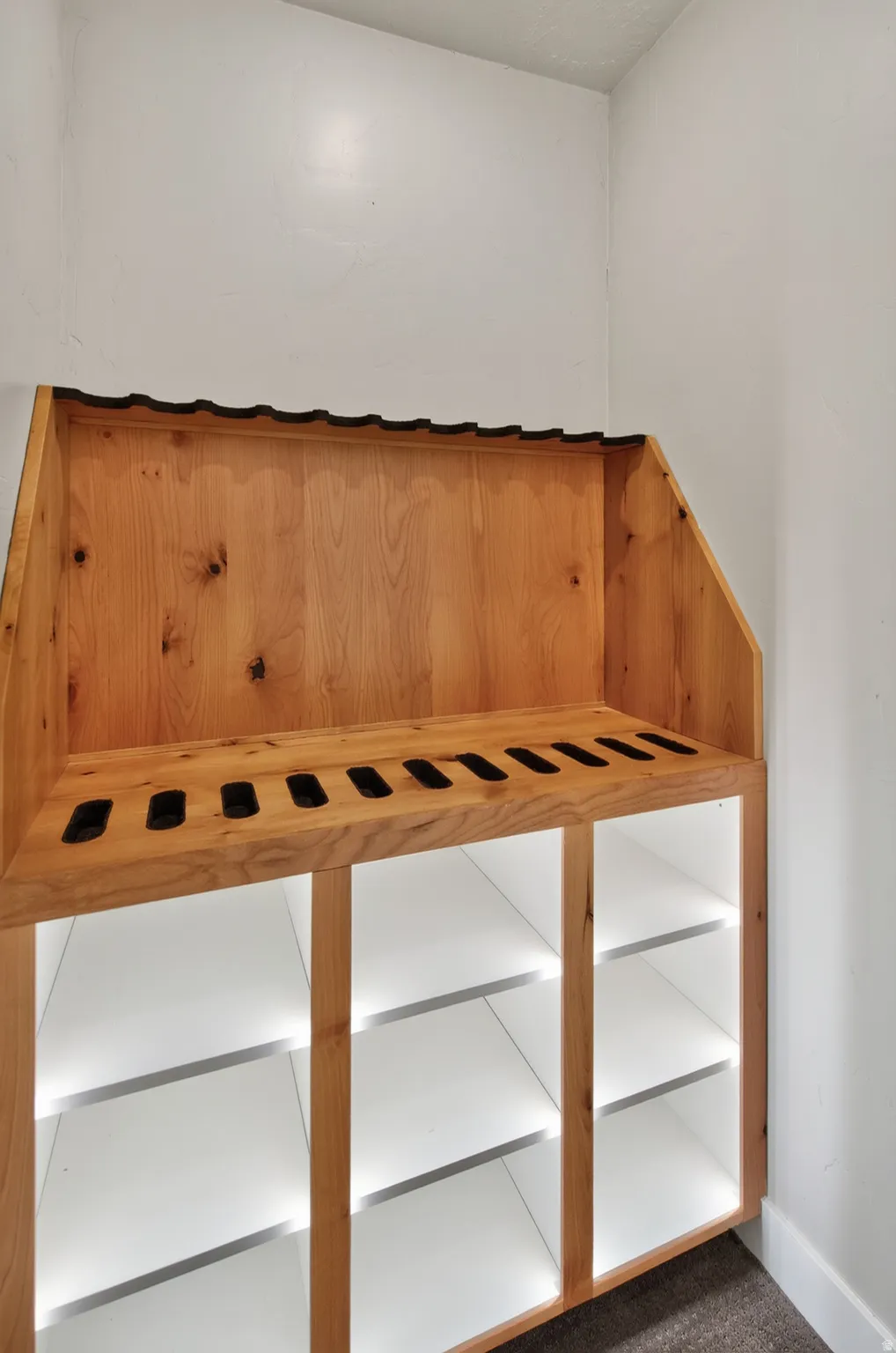 Custom-built wood-finish storage unit featuring an upper display rack and six illuminated lower cubbies