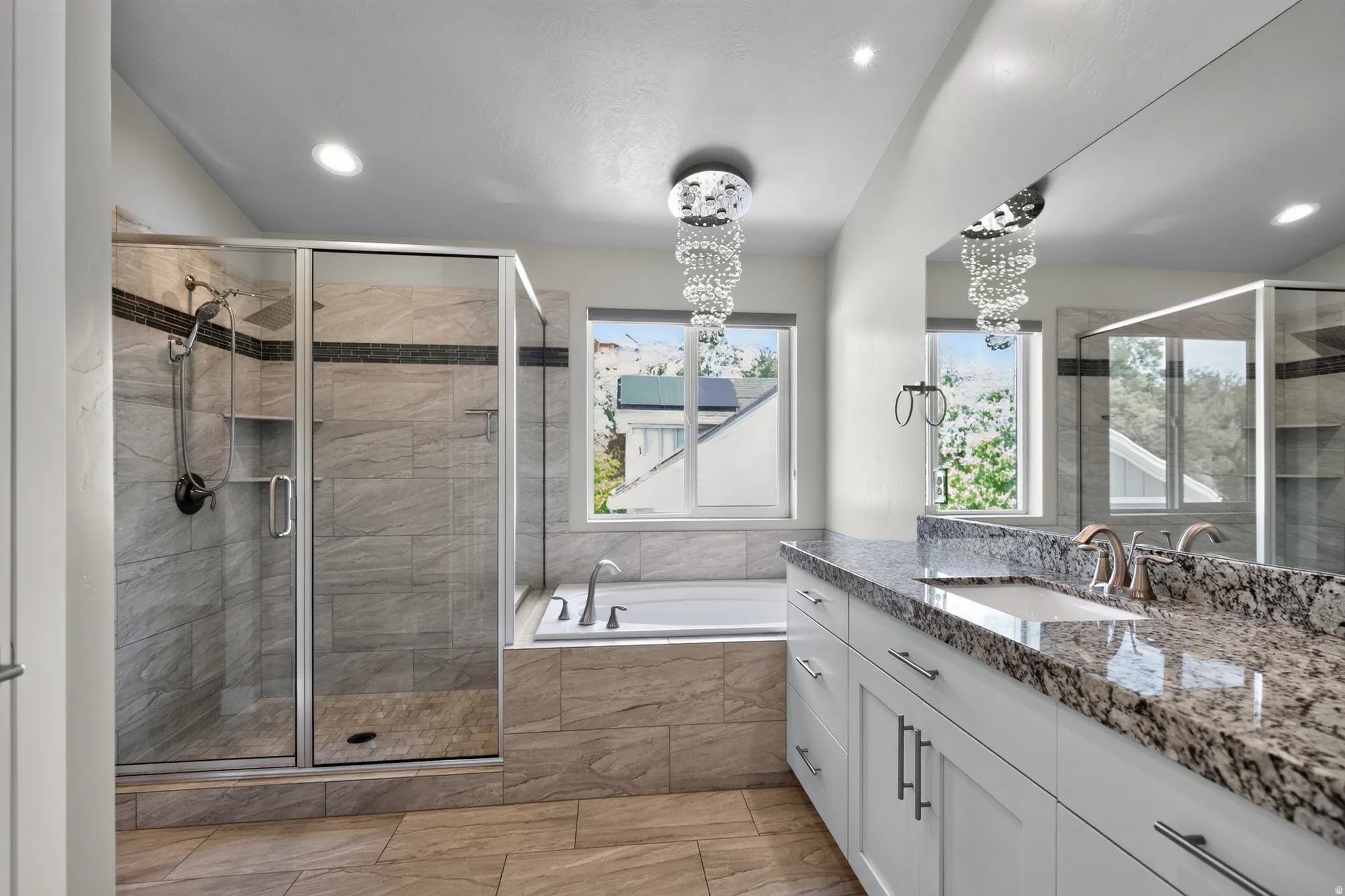 Bathroom featuring a walk-in shower with glass enclosure, a built-in bathtub, a double vanity with granite countertop, and tile flooring
