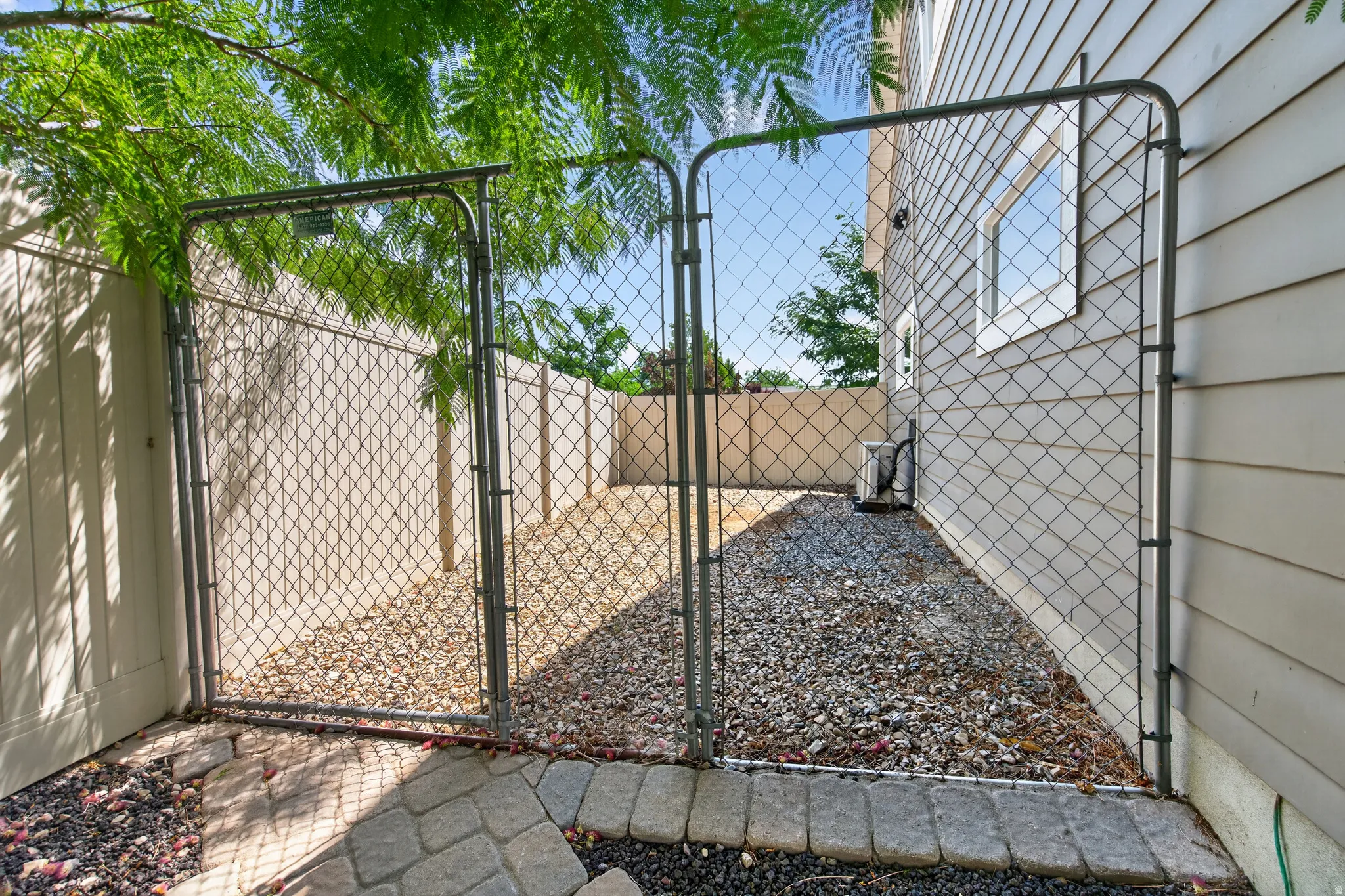 Chain link fencing enclosing a gravel-covered side yard