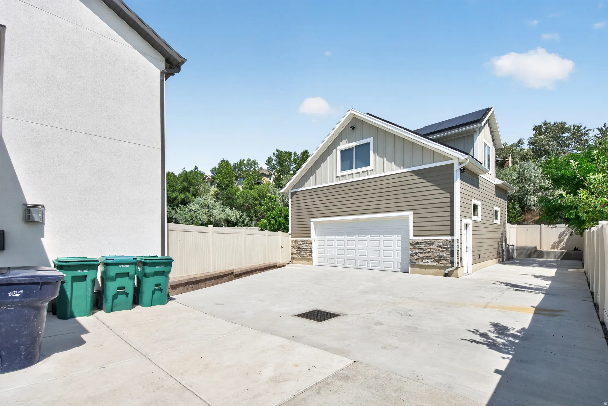 Detached garage structure featuring a paneled overhead door, horizontal siding, and stone veneer accents