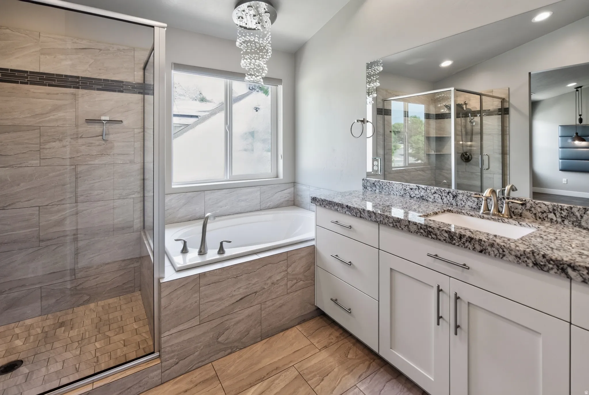 Contemporary bathroom featuring a spacious walk-in shower with tile surround and glass enclosure, a built-in soaking tub, a double vanity with granite countertop and undermount sinks, white shaker-style cabinetry, and wood-finish flooring