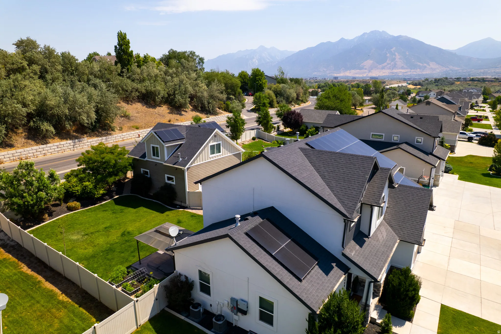 Contemporary residential property featuring solar panels, a manicured lawn, and mountain scenery