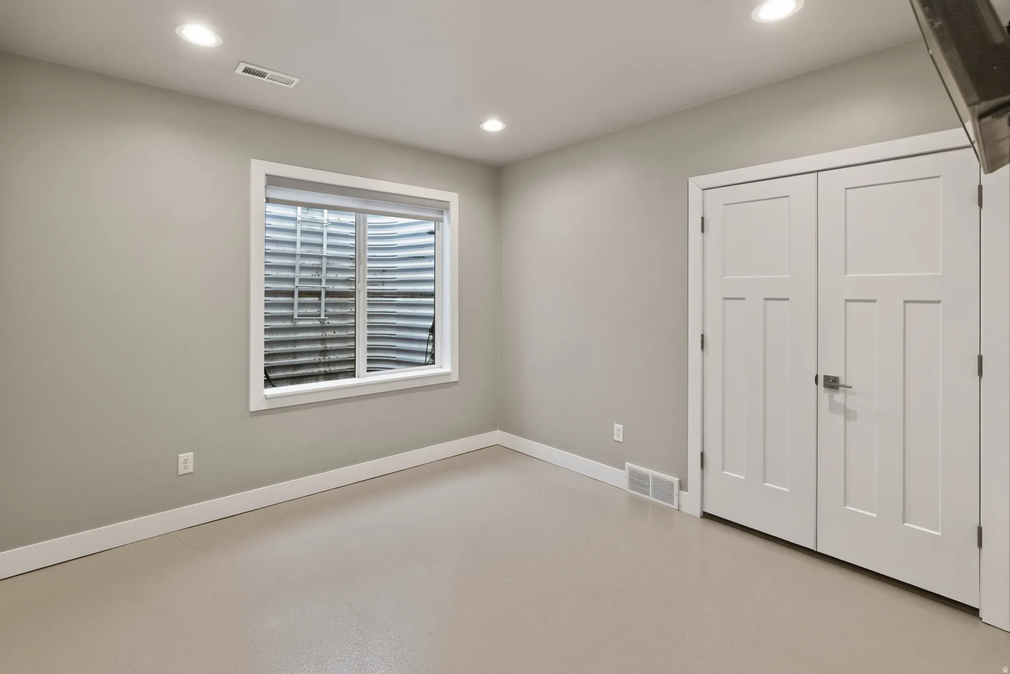 Finished interior space featuring a window well, recessed lighting, neutral wall tones, white trim, and a double-door closet with brushed nickel hardware