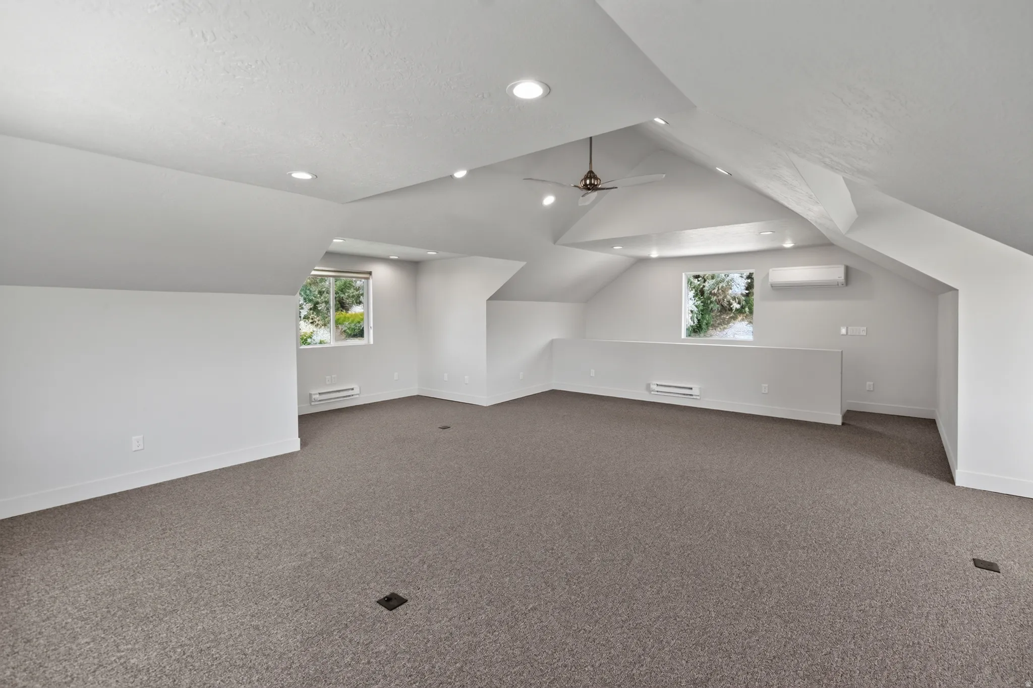 Spacious bonus room featuring vaulted ceilings, recessed lighting, neutral carpeting, and multiple windows