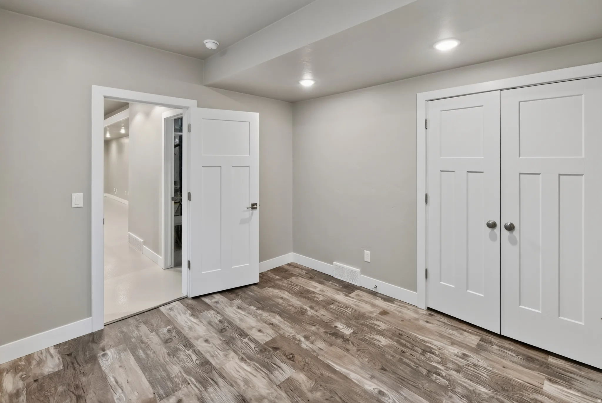 Room featuring wood-finish flooring, light grey walls, and white trim