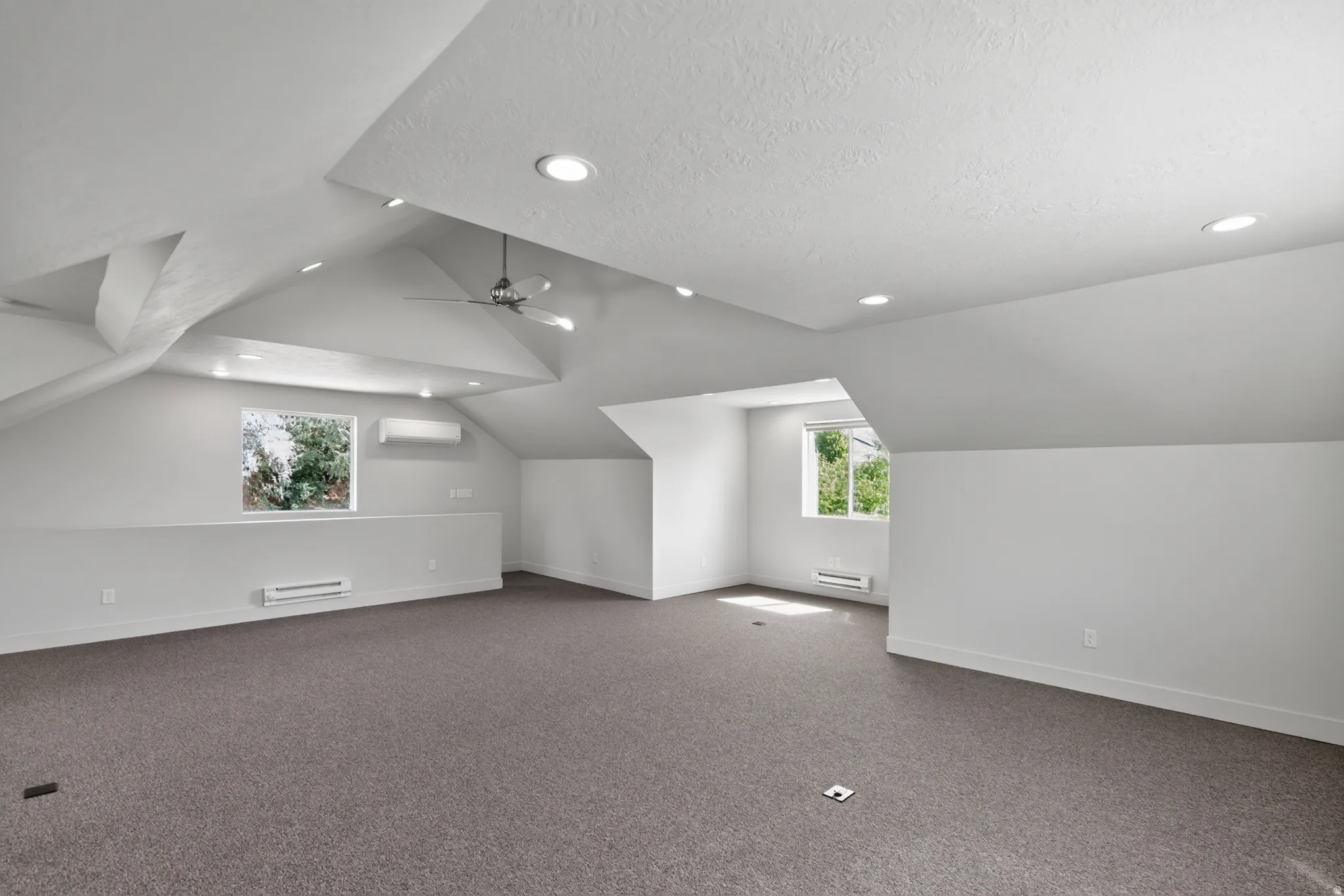 Spacious room featuring vaulted ceilings, recessed lighting, wall-to-wall carpeting, and multiple windows
