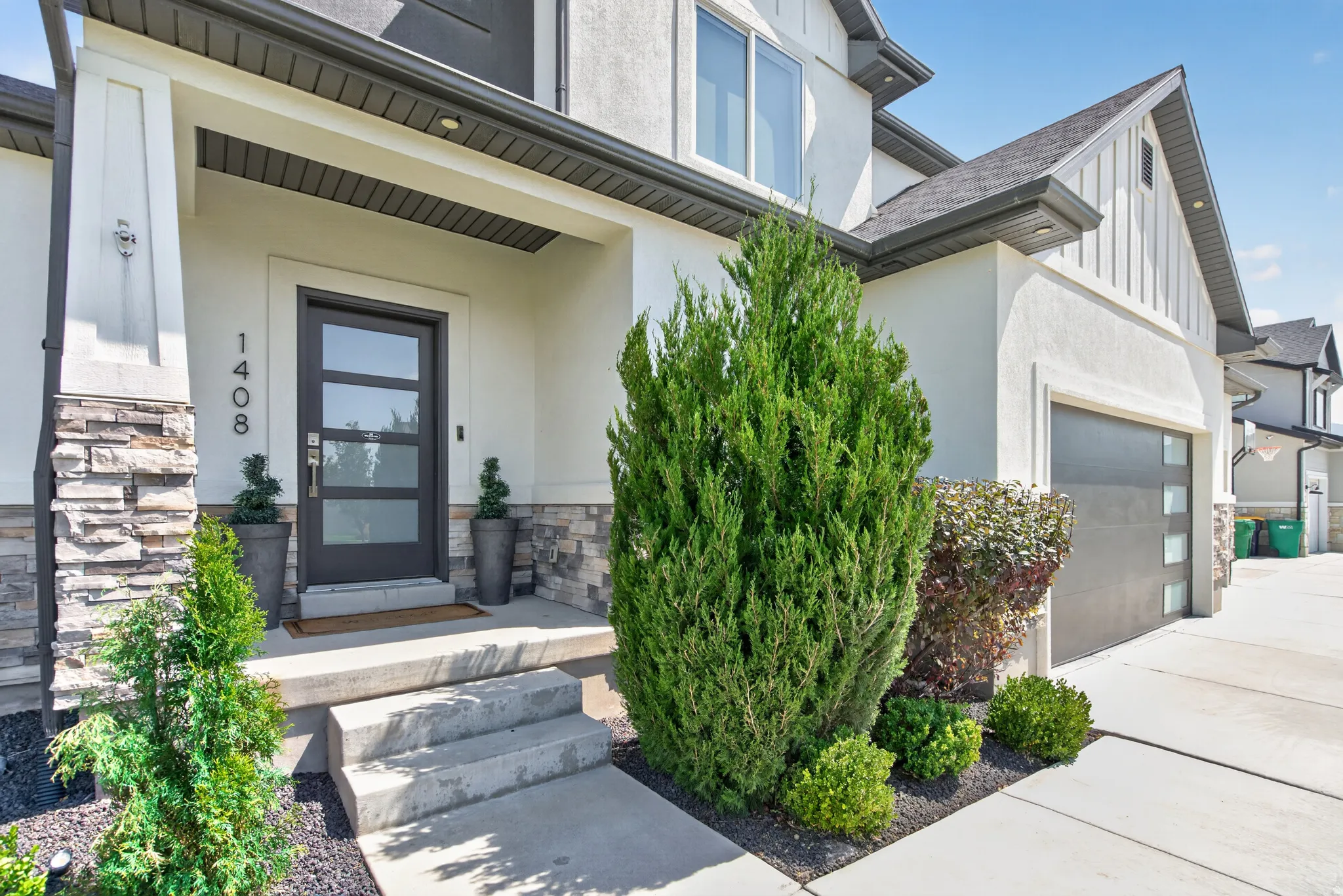 Modern gray front door with vertical window panels, set against a stone veneer and stucco exterior