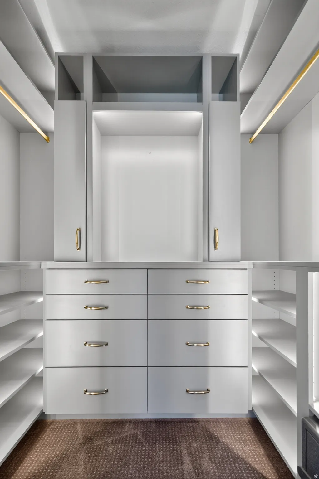 Built-in closet system featuring multiple drawers, open shelving, integrated lighting, and brass-tone hardware