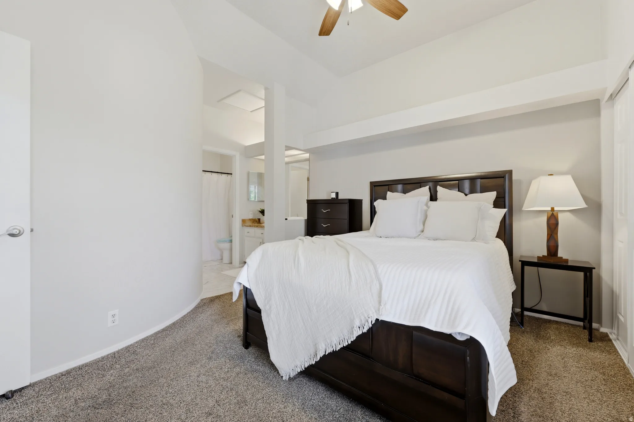 Carpeted bedroom with a vaulted ceiling and ceiling fan