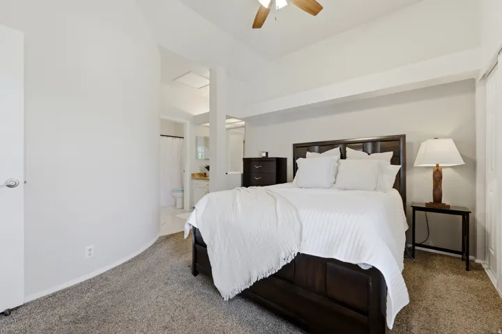 Carpeted bedroom with a vaulted ceiling and ceiling fan