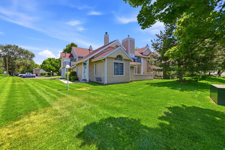 Expansive green lawn with mature trees fronting a residential structure