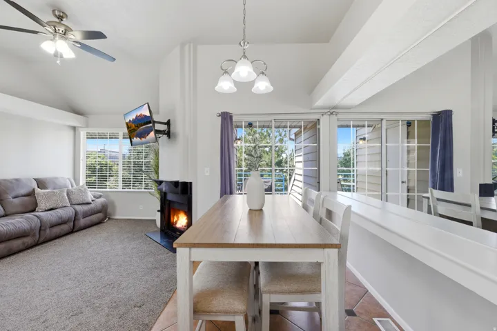 Living area featuring vaulted ceilings, a ceiling fan, and a fireplace with a black surround