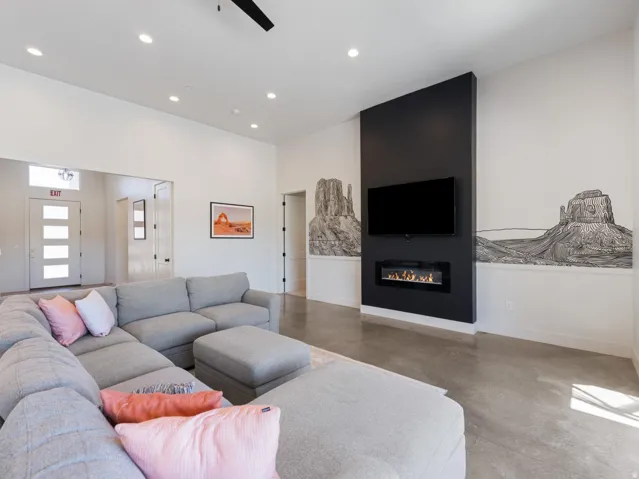 Spacious living area featuring a modern linear fireplace, high ceilings, recessed lighting, and polished concrete flooring