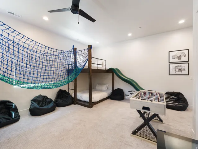 Recreational room featuring a built-in bunk bed, indoor slide, and ceiling fan