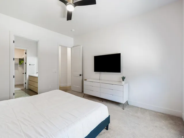 Bedroom featuring light-toned carpet flooring, white walls, and a contemporary ceiling fan
