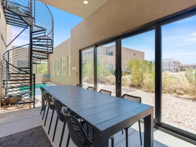 Covered patio featuring a black spiral staircase, a small plunge pool, and floor-to-ceiling glass sliding doors