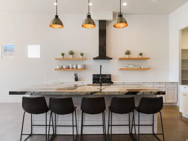 Expansive kitchen island featuring a waterfall edge, stone countertop, and integrated cooktop