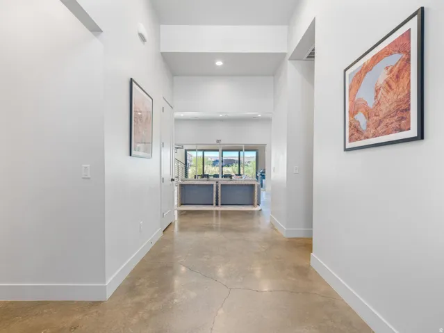 Spacious hallway featuring polished concrete flooring, recessed lighting, high ceilings, and white baseboards