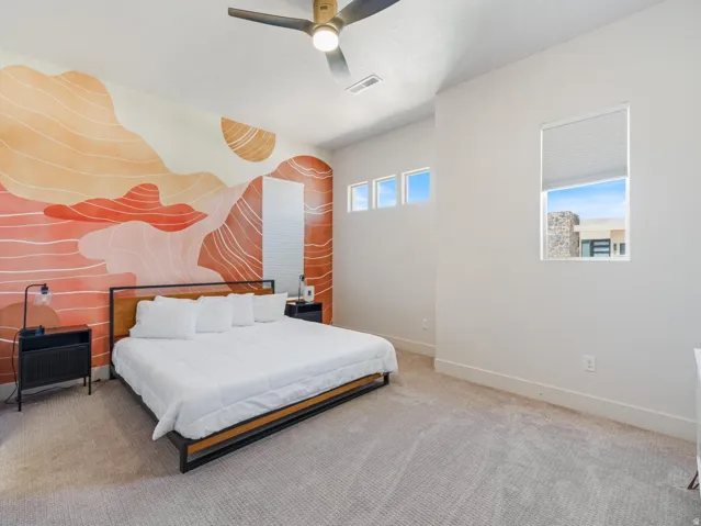 Spacious room featuring a decorative accent wall, neutral carpeting, and a contemporary ceiling fan