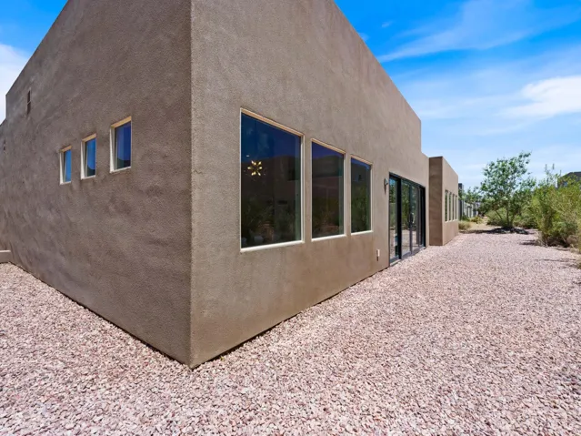 Exterior stucco facade with multiple large windows and a sliding glass door