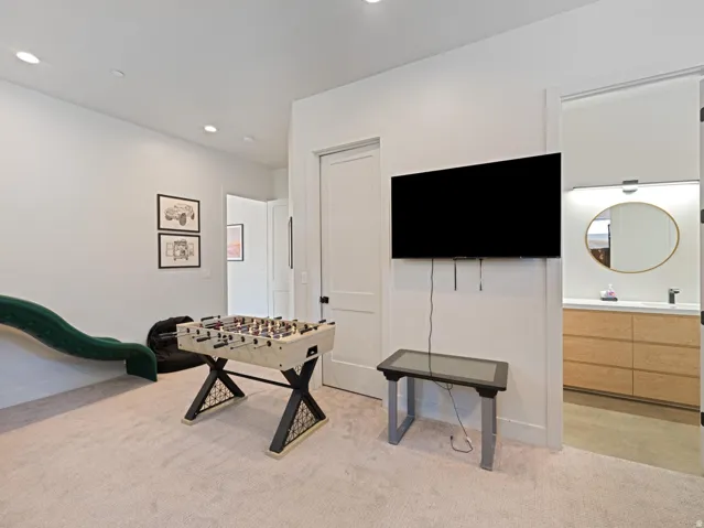 Spacious bonus room featuring plush carpeting, recessed lighting, and a wall-mounted television