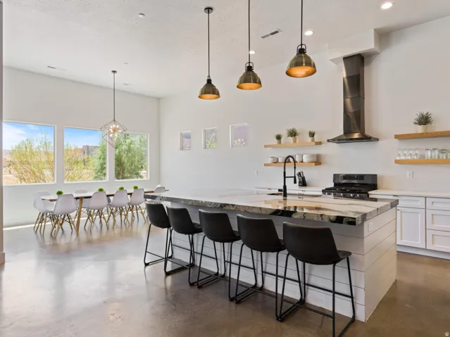 Open-concept kitchen with a large island featuring a stone countertop, an integrated sink with a matte black faucet, and a shiplap base
