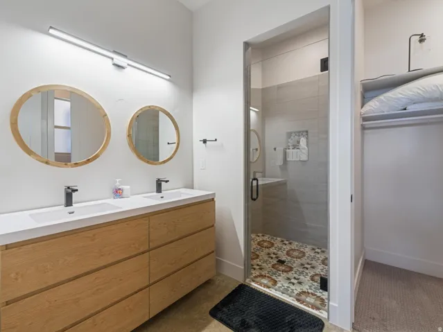 Bathroom featuring a double vanity with wood-finish cabinetry, two vessel sinks, and matte black faucets
