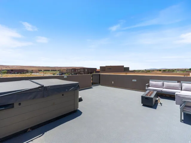 Rooftop patio featuring a built-in hot tub with cover, a dark gray fire pit, and durable gray flooring