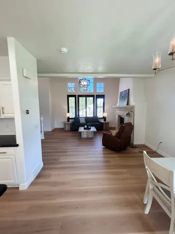 Wood-finish flooring throughout, bright living space with high ceilings, recessed lighting, and a stone fireplace