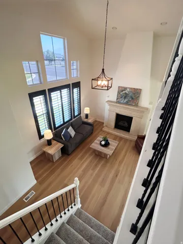 Vaulted ceiling, wood-finish flooring, stone fireplace, wrought iron balusters, and plantation shutters