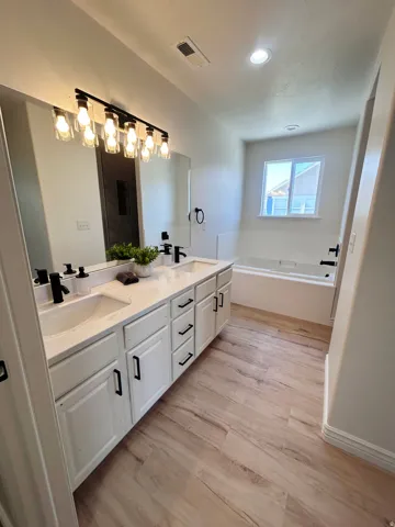 Dual vanity with white cabinetry, matte black hardware, and integrated sinks