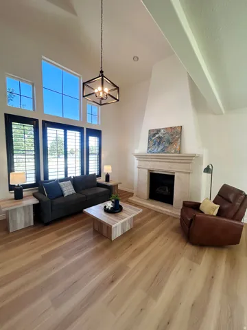 Vaulted ceilings, wood-finish flooring, and a stone-clad fireplace with a hearth
