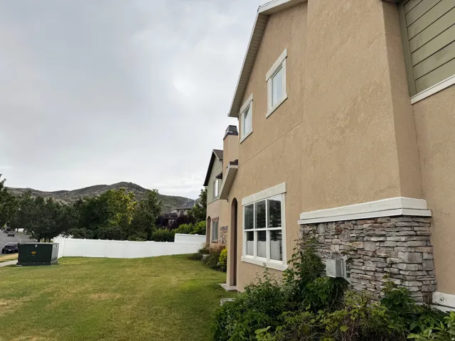 Stucco exterior with stone veneer accents, white window trim, and a manicured lawn