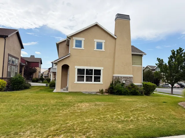 Stucco exterior with stone accenting, prominent chimney, a covered entryway, and white-framed windows
