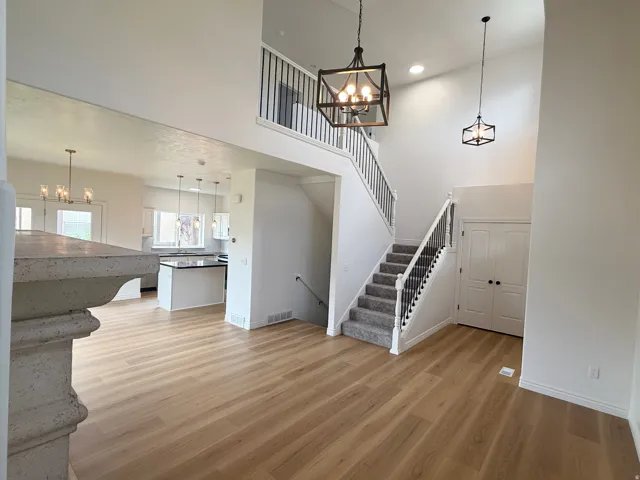 Two-story foyer with wood-finish flooring and a carpeted staircase featuring black wrought iron balusters