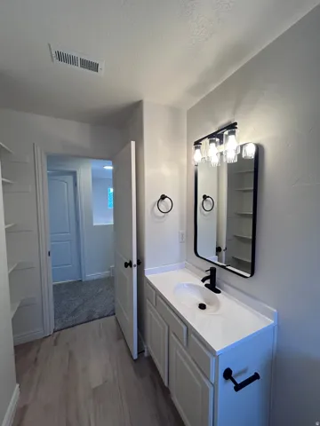 Modern vanity featuring a white countertop with an integrated sink, matte black faucet, and coordinating mirror with a black frame