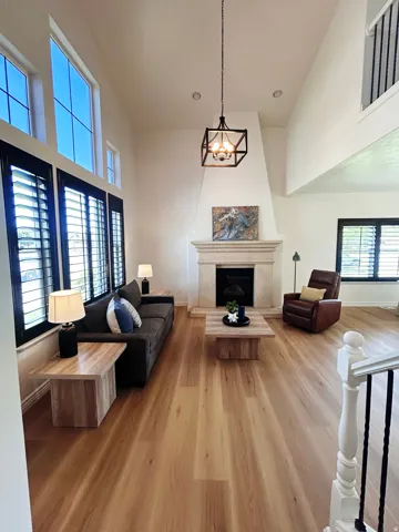 Vaulted ceilings, wood-finish flooring, stone-clad fireplace, plantation shutters, and an open spindle staircase