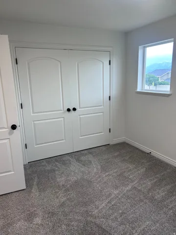 Interior room featuring neutral gray carpeting, white walls, and white baseboards