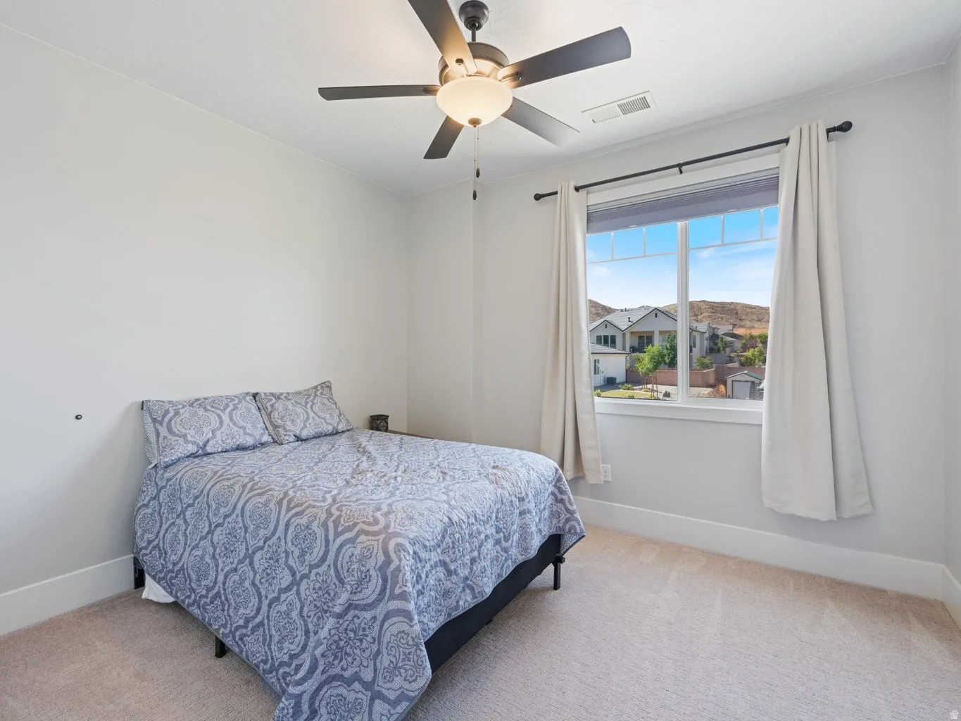 Carpeted room featuring a ceiling fan with integrated lighting, a large window with white trim, and a window blind