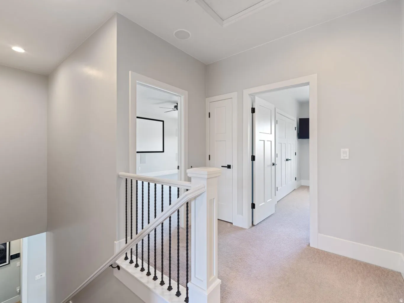 Staircase featuring white newel posts and handrail with black wrought iron balusters