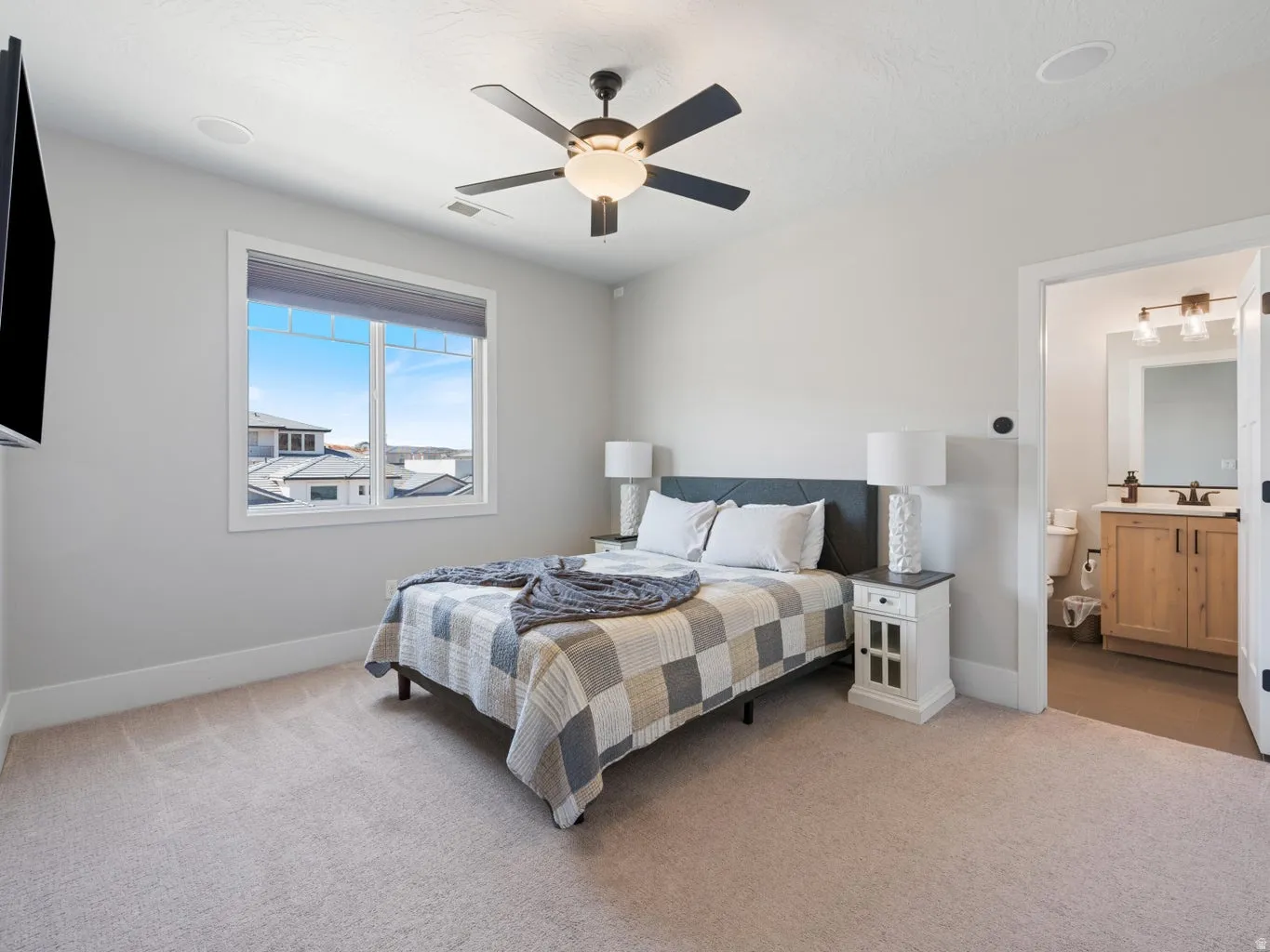 Recessed lighting, ceiling fan, and carpeted flooring define this bright room