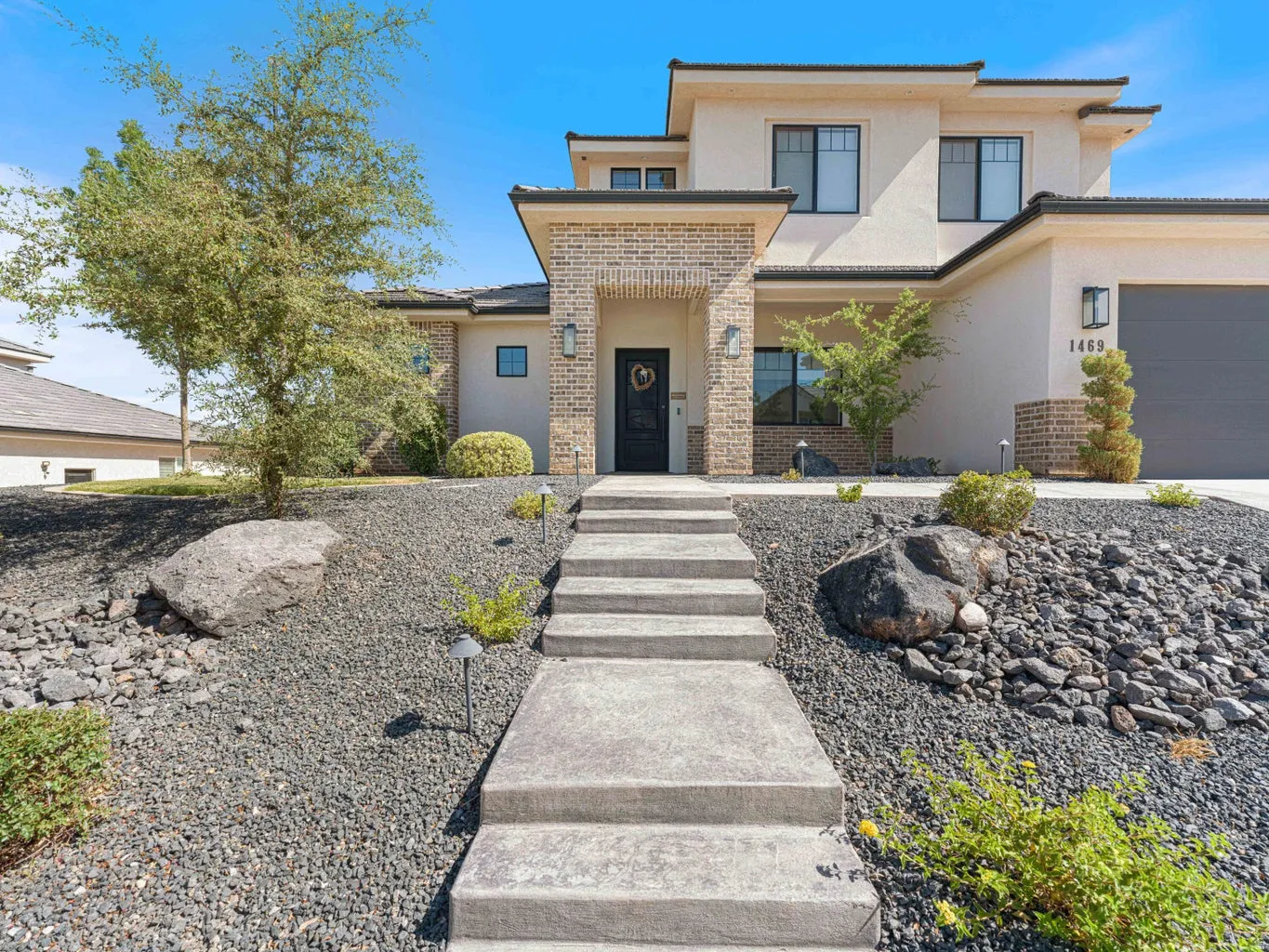 Contemporary facade featuring stucco and brick accents, a dark entry door, and multi-pane windows
