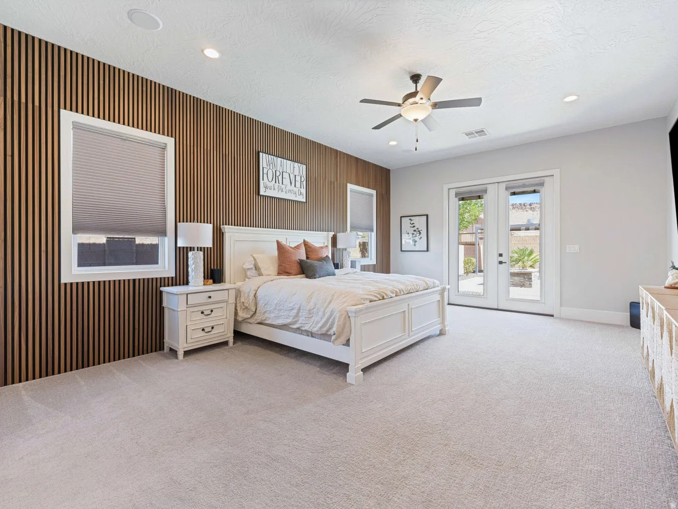 Room featuring a textured wood-panel accent wall, recessed lighting, ceiling fan, carpet flooring, and a double-door exterior entry