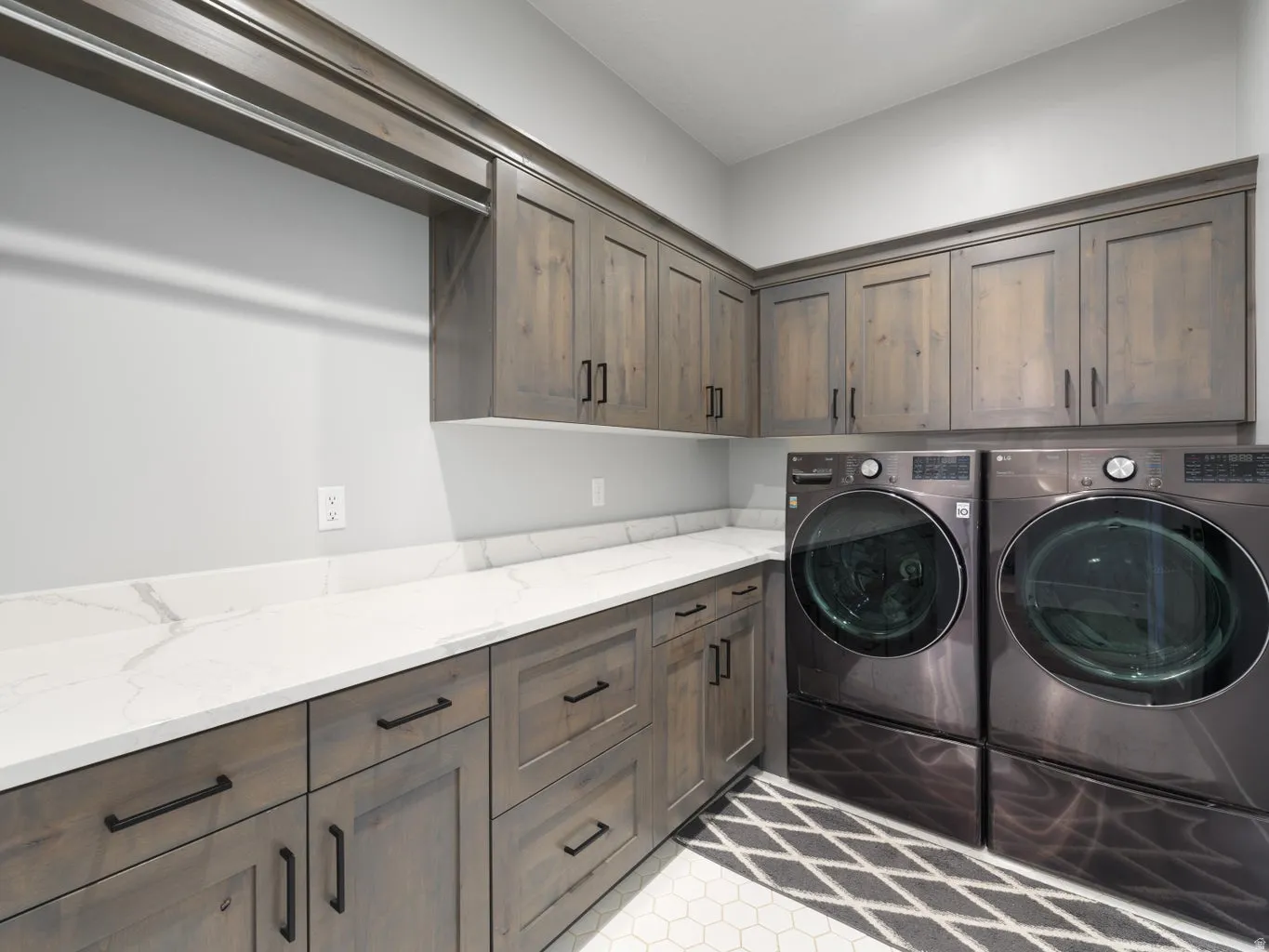 Laundry room featuring extensive wood-finish cabinetry, white countertops, and a built-in hanging rod