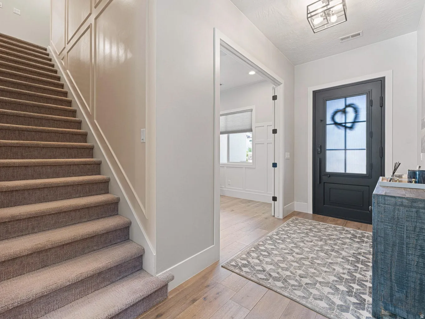 Entry foyer featuring a dark-toned front door with frosted glass and a metal grate