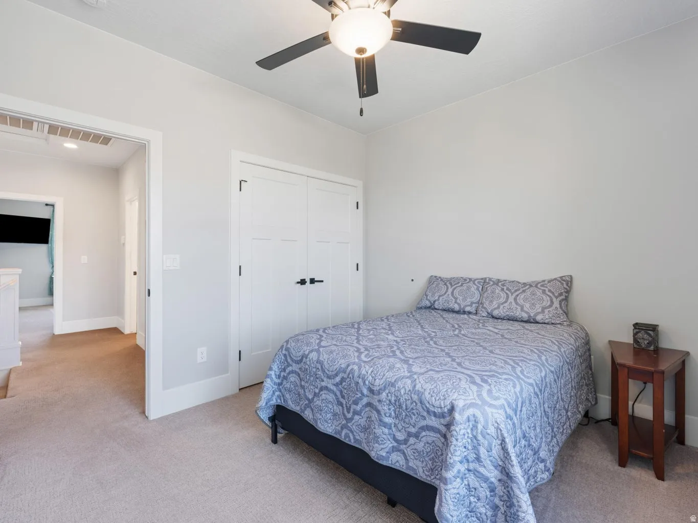 Carpeted room featuring a ceiling fan with integrated lighting, white baseboards, and a double-door closet with dark hardware