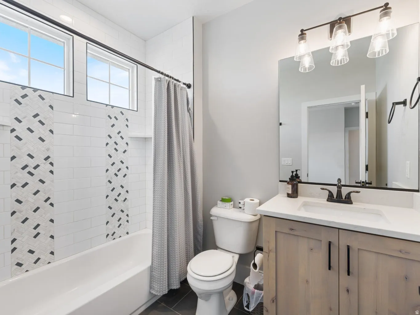 Contemporary bathroom featuring a white bathtub with subway tile surround and decorative mosaic accents