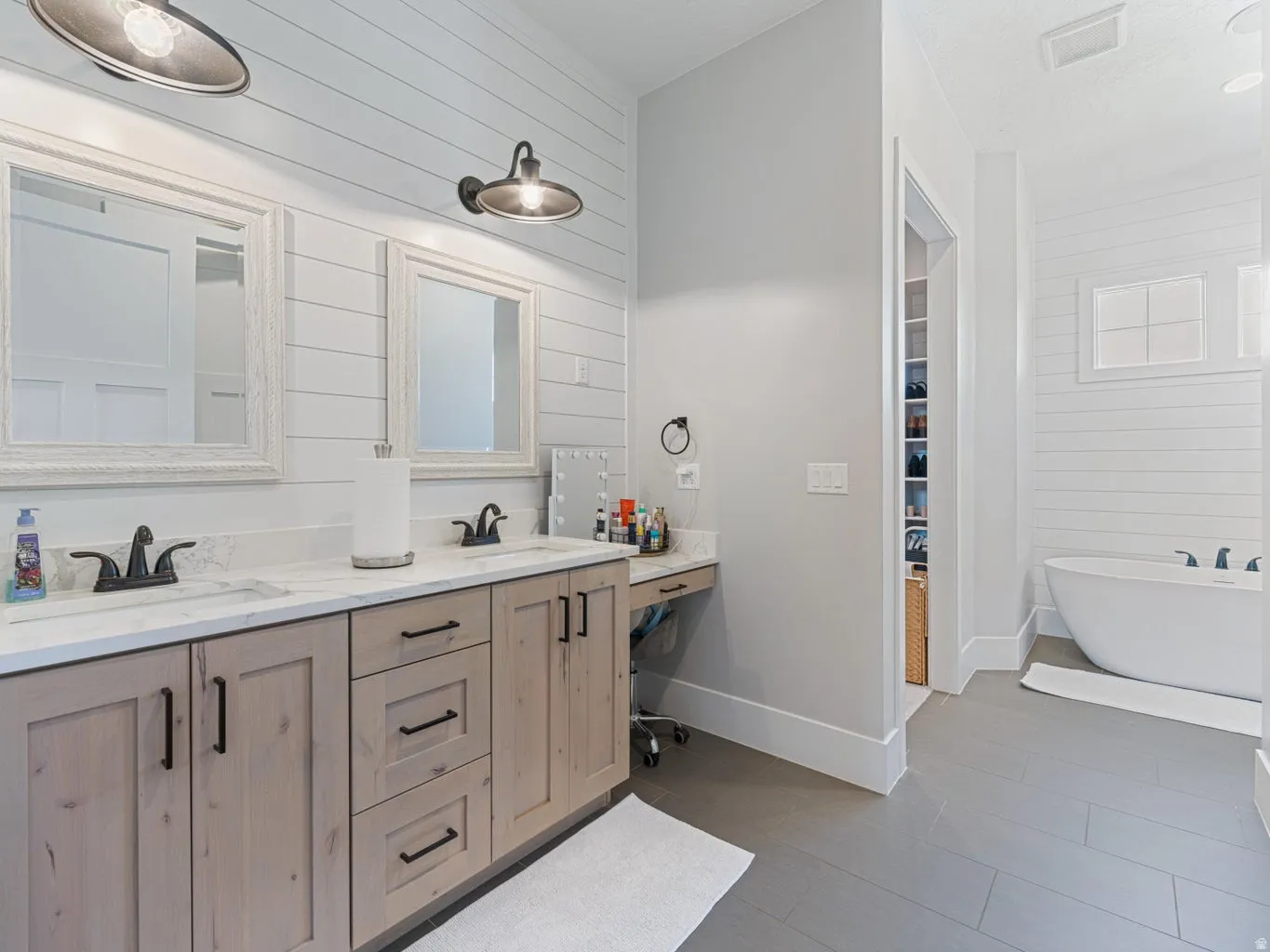 Dual vanity with light wood-finish cabinetry, white countertops, and matte black fixtures