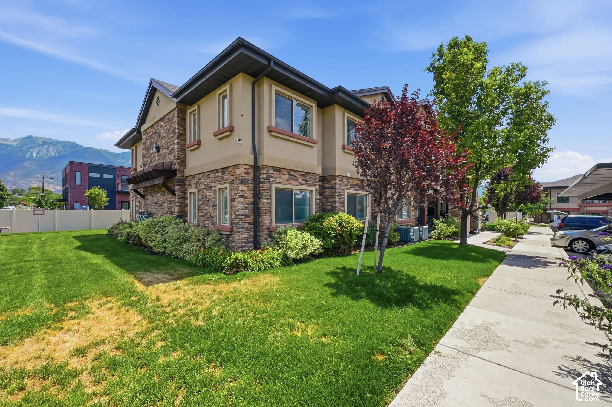 Multi-story exterior featuring a stone and stucco facade, dark trim, and multiple windows