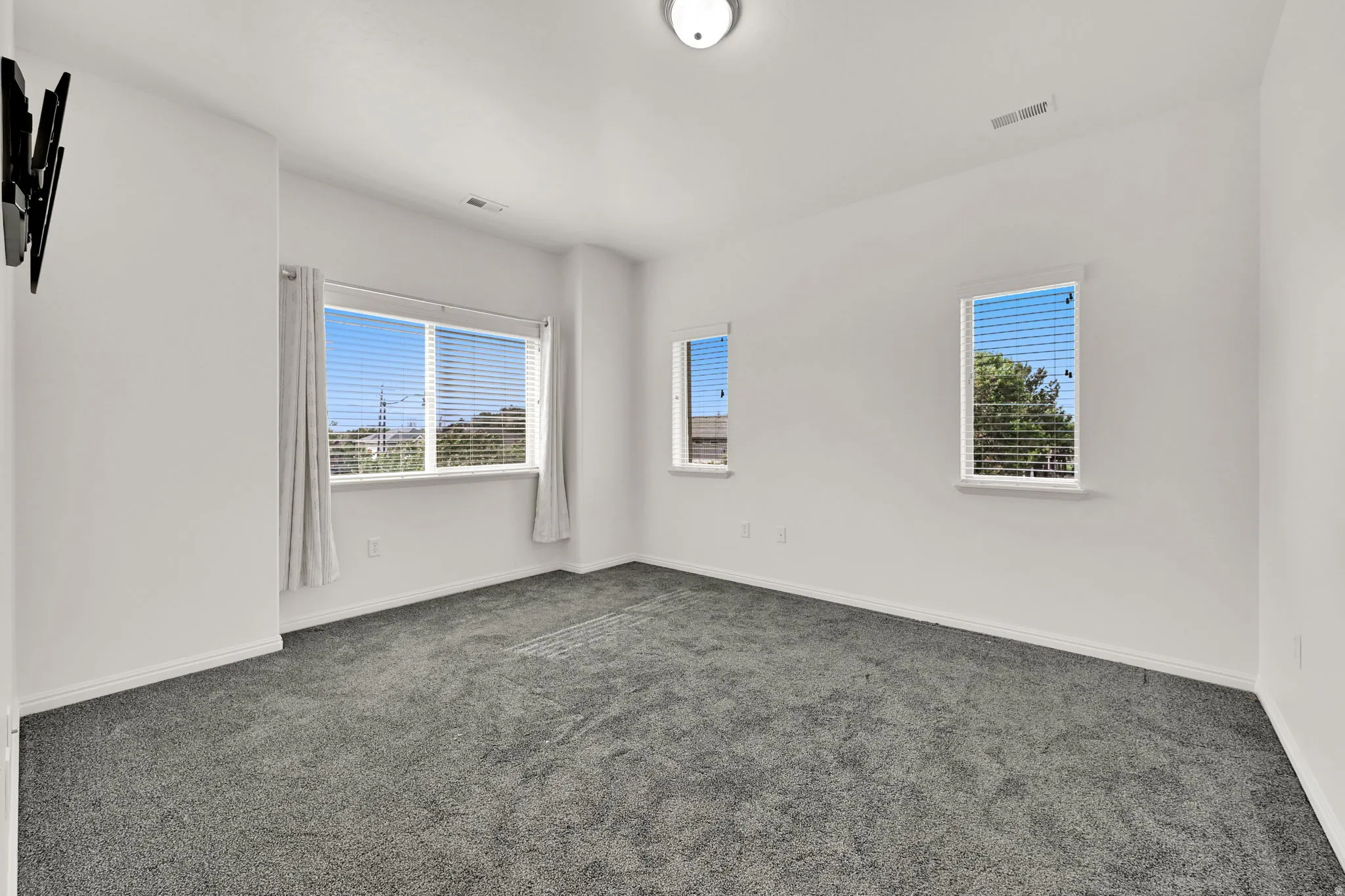 Plush gray carpeting, multiple windows with blinds, and recessed ceiling light fixture